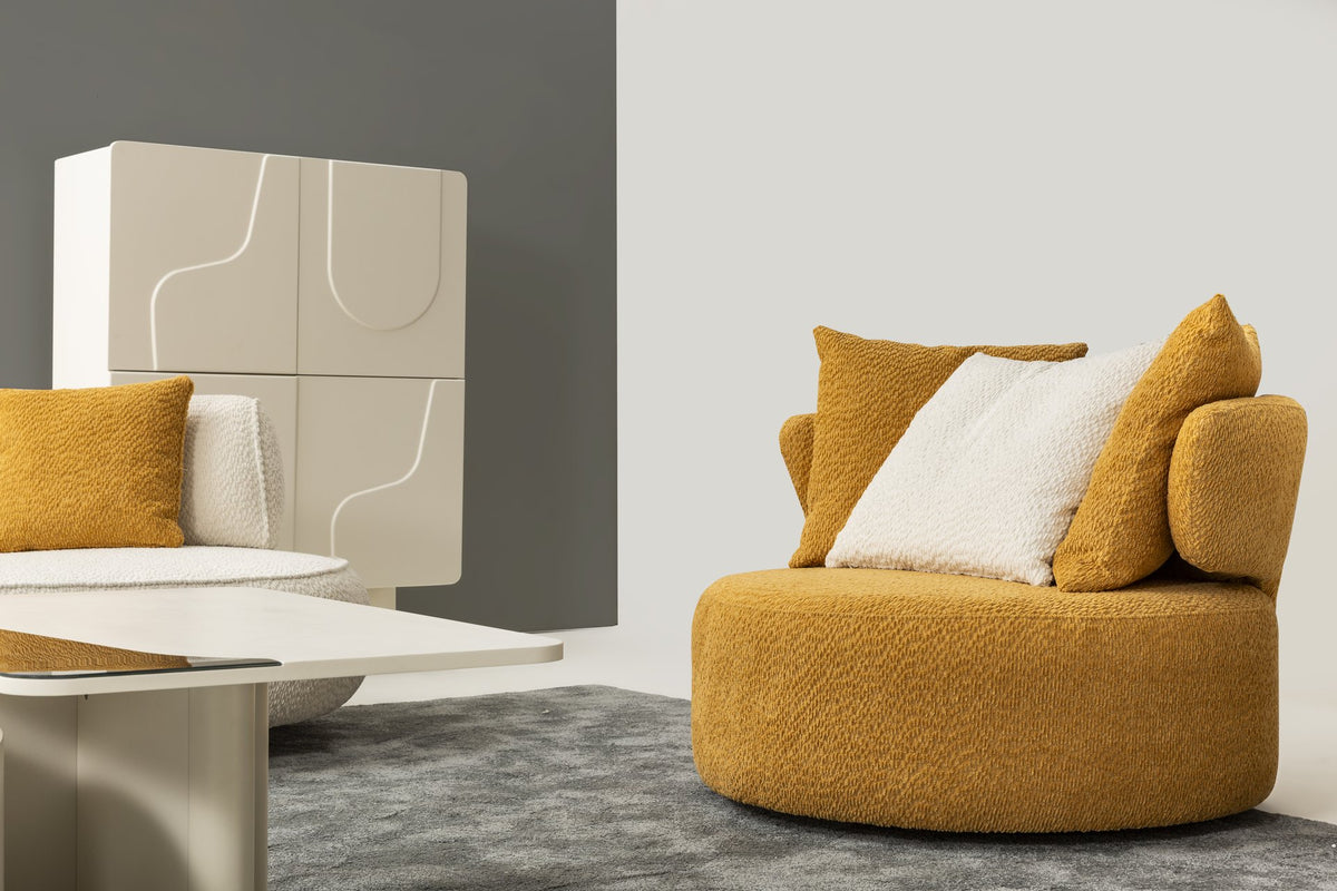Fotoliu rotund Ozel în bouclé muștar, cu spătar-rulou curbat, șezut lat și două perne decorative, în living modern